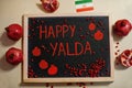 Happy Yalda night. Iranian traditional holiday. Pomegranate inscription on blackboard, flat lay
