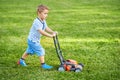 Happy 3 year old boy having fun mowing lawn Royalty Free Stock Photo