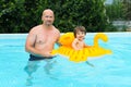 Happy 2 years boy on inflatable toy swimms with his father in po