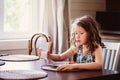 happy 8 years old child girl having breakfast in country kitchen, drinking milk and eating toast Royalty Free Stock Photo