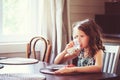 Happy 8 years old child girl having breakfast in country kitchen, drinking milk and eating toast Royalty Free Stock Photo