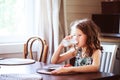 happy 8 years old child girl having breakfast in country kitchen