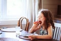 Happy 8 years old child girl having breakfast in country kitchen Royalty Free Stock Photo