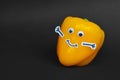 Happy Yellow Paprika vegetable with goggle eyes, smile mouth and arms on dark black background