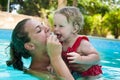 Happy young active mother and curly little baby having fun in a swimming pool Royalty Free Stock Photo