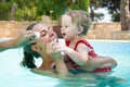 Happy young active mother and curly little baby having fun in a swimming pool Royalty Free Stock Photo