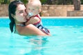 Happy young active mother and curly little baby having fun in a swimming pool Royalty Free Stock Photo