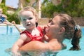 Happy young active mother and curly little baby having fun in a swimming pool Royalty Free Stock Photo