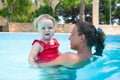 Happy young active mother and curly little baby having fun in a swimming pool Royalty Free Stock Photo