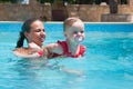 Happy young active mother and curly little baby having fun in a swimming pool Royalty Free Stock Photo