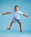 Happy young adorable little hispanic boy jumping in the air, isolated on blue background. Funny preschooler kid Royalty Free Stock Photo