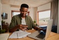 Happy young adult black male smiling, making online payment on laptop in modern apartment. Royalty Free Stock Photo