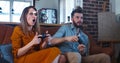 Happy young adult Caucasian man and woman have big fun video gaming on console against each other at home slow motion.