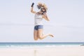 Happy young adult caucasian woman jump and have fun at tghe beach in alone free summer holiday vacation listening music with Royalty Free Stock Photo