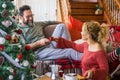 Happy young adult couple at home enjoying christmas morning in december taking coffee and breakfast together. Man smile to a woman