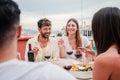 Happy young adult couple smiling, laughing and dining with their friends on a friendly lunch party celebration. Two Royalty Free Stock Photo