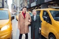 Happy young adult couple walking out from yellow taxi in New York City street for shopping. Royalty Free Stock Photo