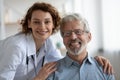 Happy young adult female doctor embracing senior male patient, portrait Royalty Free Stock Photo