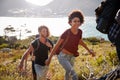 Happy young adult friends hiking uphill near the coast, close up, backlit Royalty Free Stock Photo