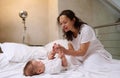 Happy delightful affectionate young mother caring of her newborn baby boy, stroking and kissing his little feet and toes Royalty Free Stock Photo