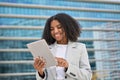 Happy young African American business woman holding tablet standing in city street. Royalty Free Stock Photo