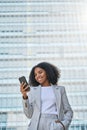 Happy young African American business woman using cell phone outdoors. Royalty Free Stock Photo
