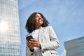 Happy young African American business woman using phone standing in city street. Royalty Free Stock Photo