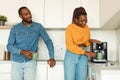 Happy young african american couple drinking morning coffee, woman using modern coffee machine in kitchen interior Royalty Free Stock Photo