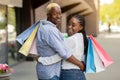 Happy young african american couple walking in town after shopping with colorful bags Royalty Free Stock Photo