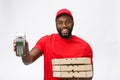 Happy young African American delivery man holding up an electronic card payment machine and delivery product. Isolated Royalty Free Stock Photo