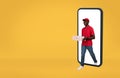 Happy young african american delivery man in uniform coming out of smartphone with blank screen with many pizza boxes Royalty Free Stock Photo