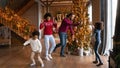 Happy biracial family with kids dance near fir tree Royalty Free Stock Photo