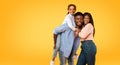 Happy young african american family posing, man giving piggy back ride for his daughter, yellow background, free space Royalty Free Stock Photo