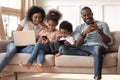 Black family with kids relax on couch using gadgets Royalty Free Stock Photo