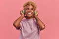 Happy young African American female relaxed with a great song has broad smile, touches headphones, listens to music Royalty Free Stock Photo