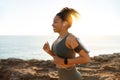 Happy young african american female in sports wear, headphones with smartphone running in morning