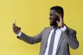 Happy young african american guy in casual t-shirt posing isolated on yellow orange background Royalty Free Stock Photo