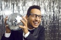 Happy young African American man in a suit and glasses holding a disco ball and smiling Royalty Free Stock Photo