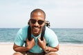 Happy young African-American hipster wearing t-shirt and sunglasses walking at summer day on the beach with backpack. Royalty Free Stock Photo