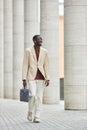 Happy young African American male solopreneur with handbag taking walk