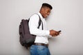 Happy young african american male student holding cellphone by gray wall Royalty Free Stock Photo