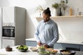 Happy young African American man cooking in modern kitchen. Royalty Free Stock Photo