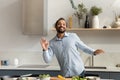 Happy young African American man dancing, cooking food. Royalty Free Stock Photo