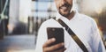 Happy young African American man in headphone walking at sunny city and enjoying to listen to music on his smart phone Royalty Free Stock Photo