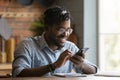 Happy young african american man sit at table use phone Royalty Free Stock Photo