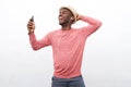 Happy young african american man listening to music with smart phone and earphones against white background Royalty Free Stock Photo