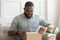 Happy young african american man unboxing delivery parcel. Royalty Free Stock Photo