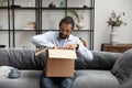 Happy young African American man unpacking cardboard box. Royalty Free Stock Photo