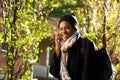 Happy young african american man walking in city park while talking with cellphone Royalty Free Stock Photo