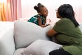 Happy young African American mother having fun with daughter child girl playing and hugging in bedroom at home Royalty Free Stock Photo